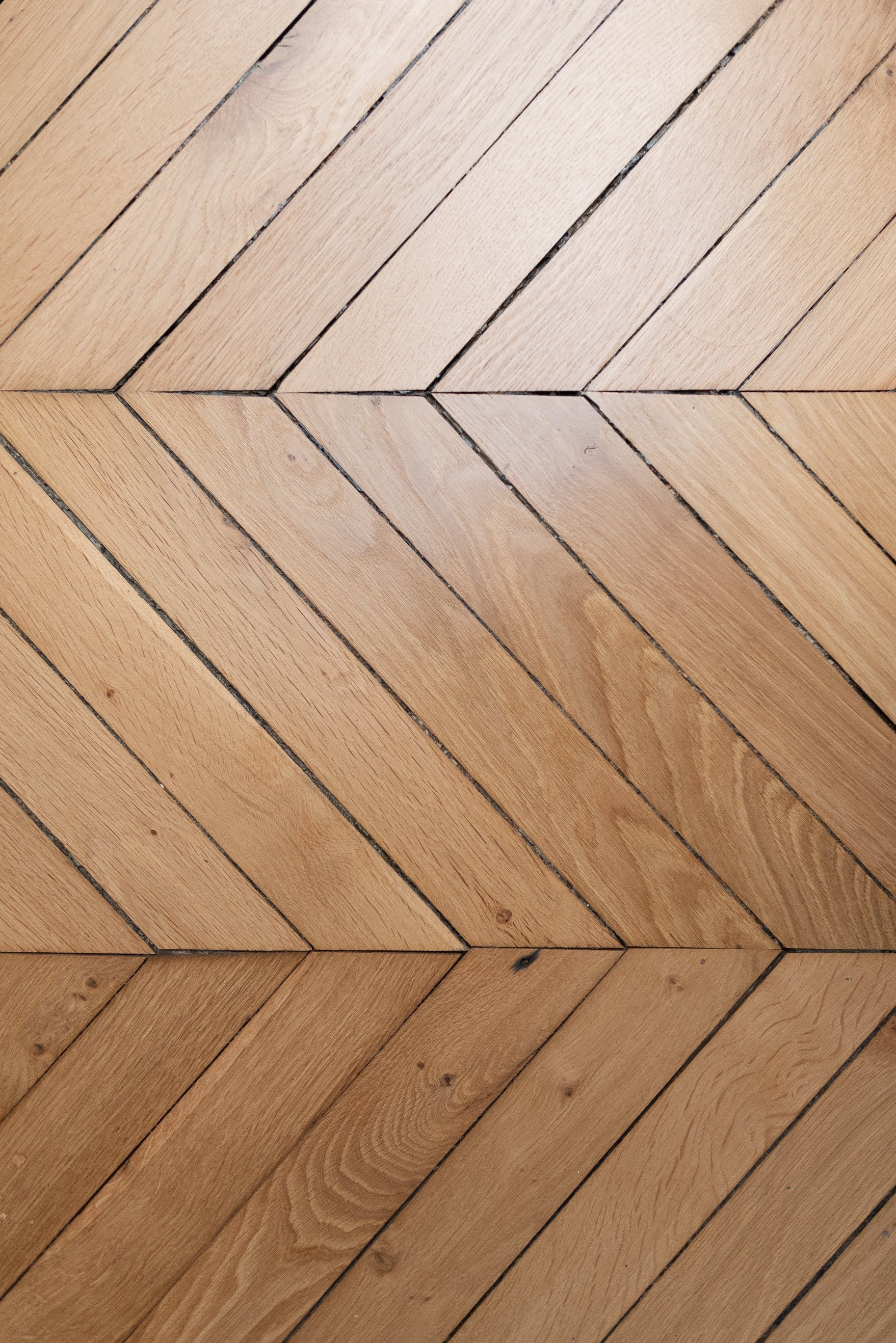 Un plancher en bois avec un motif à chevrons dans un couloir.