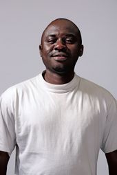 Un homme porte un t-shirt blanc et sourit.