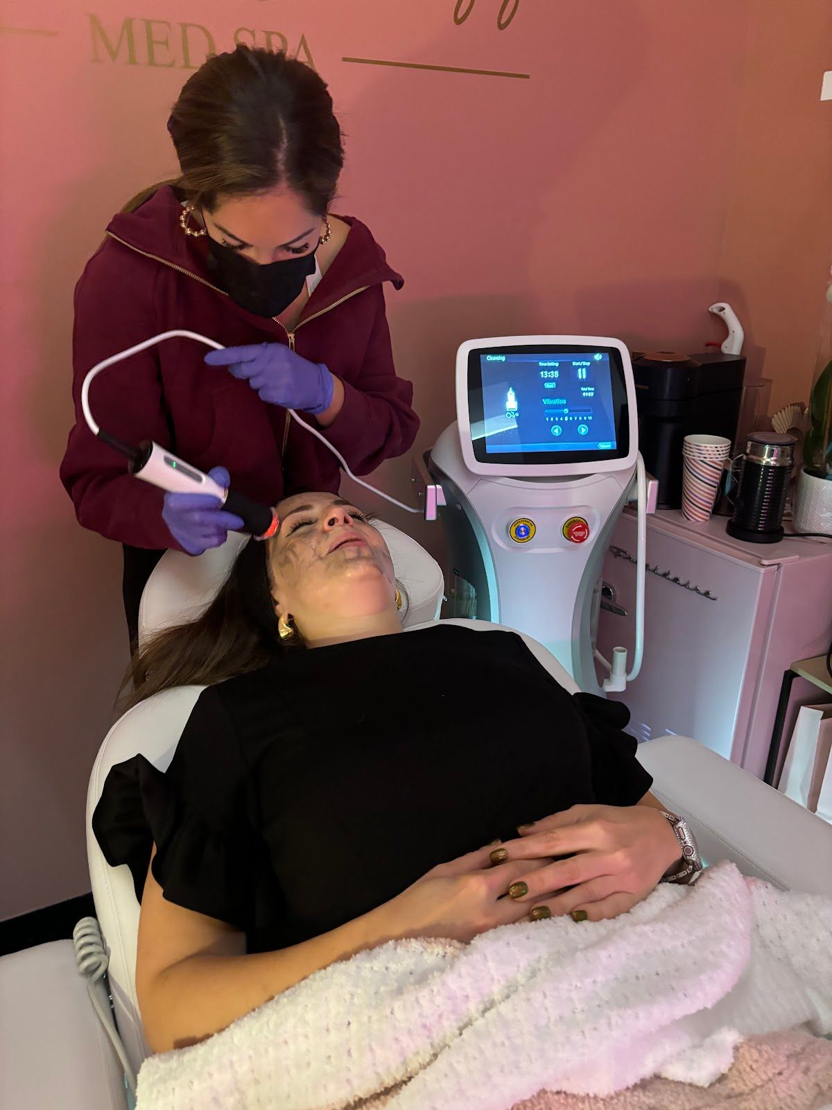 A woman is laying in a chair getting a treatment on her face.