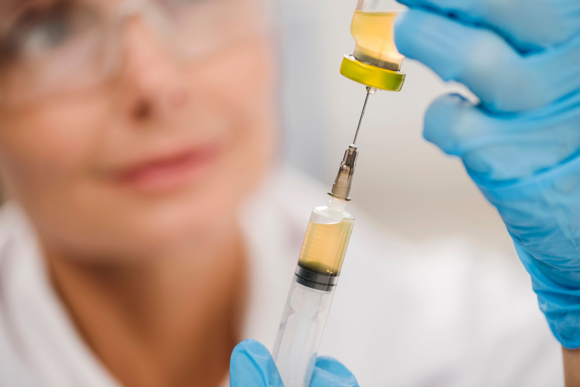 A woman is holding a syringe with a yellow liquid in it.