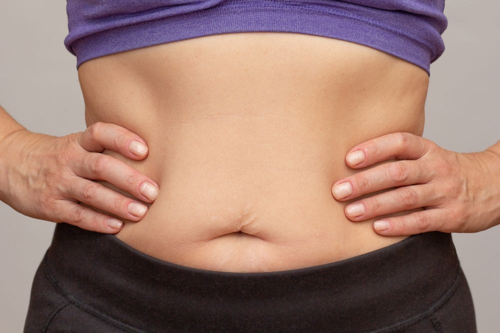 A woman is holding her hands on her stomach.