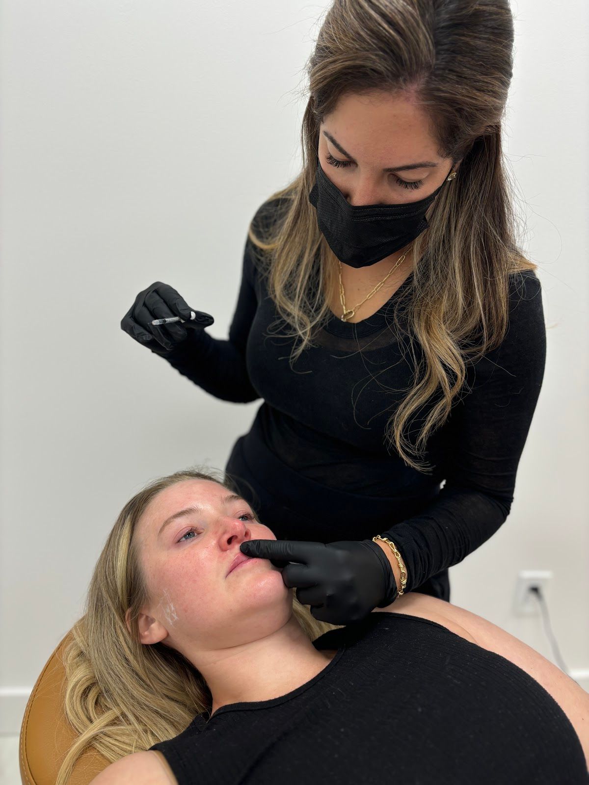 Woman receiving lip filler injection from a healthcare professional wearing a mask and gloves.