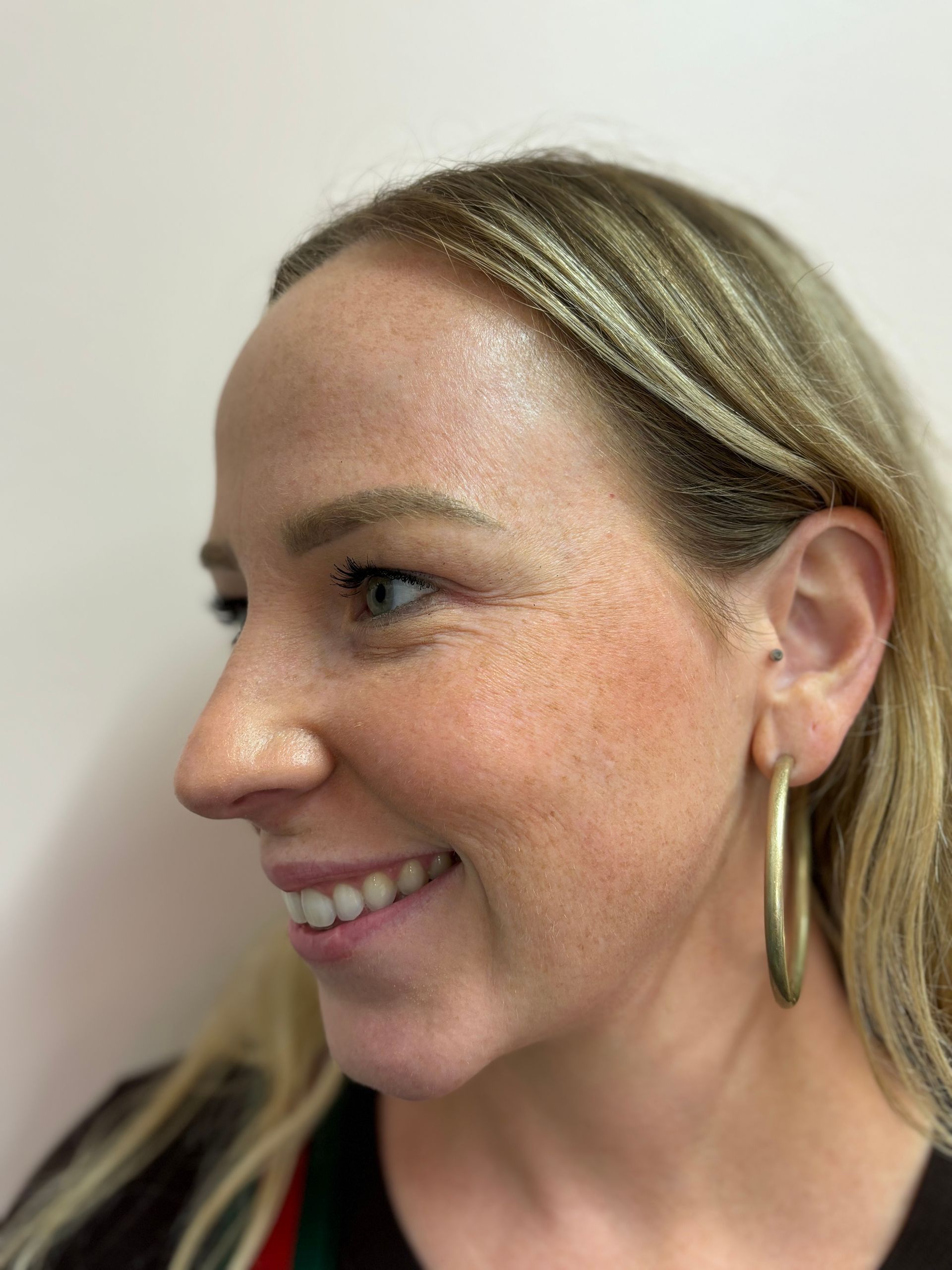 A close up of a woman wearing hoop earrings and smiling.