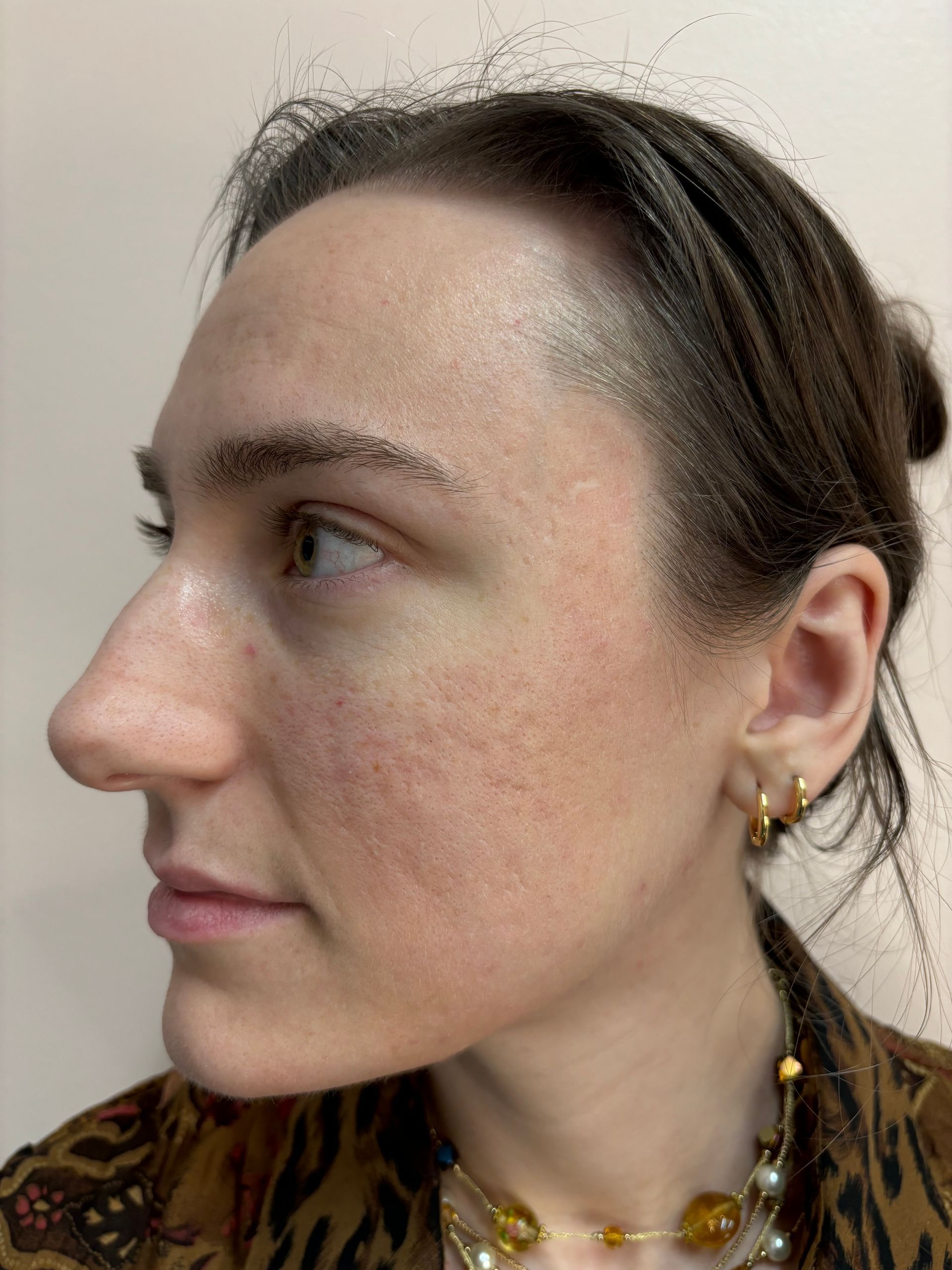 A close up of a woman 's face with a bun and earrings.