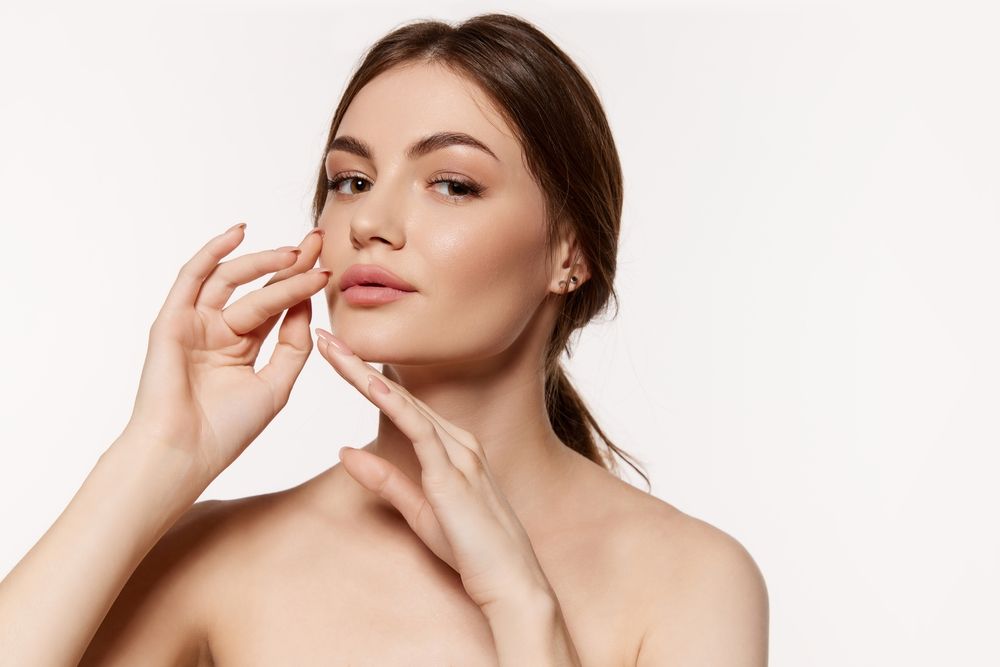 A woman wearing a mask is giving a woman an injection in her face