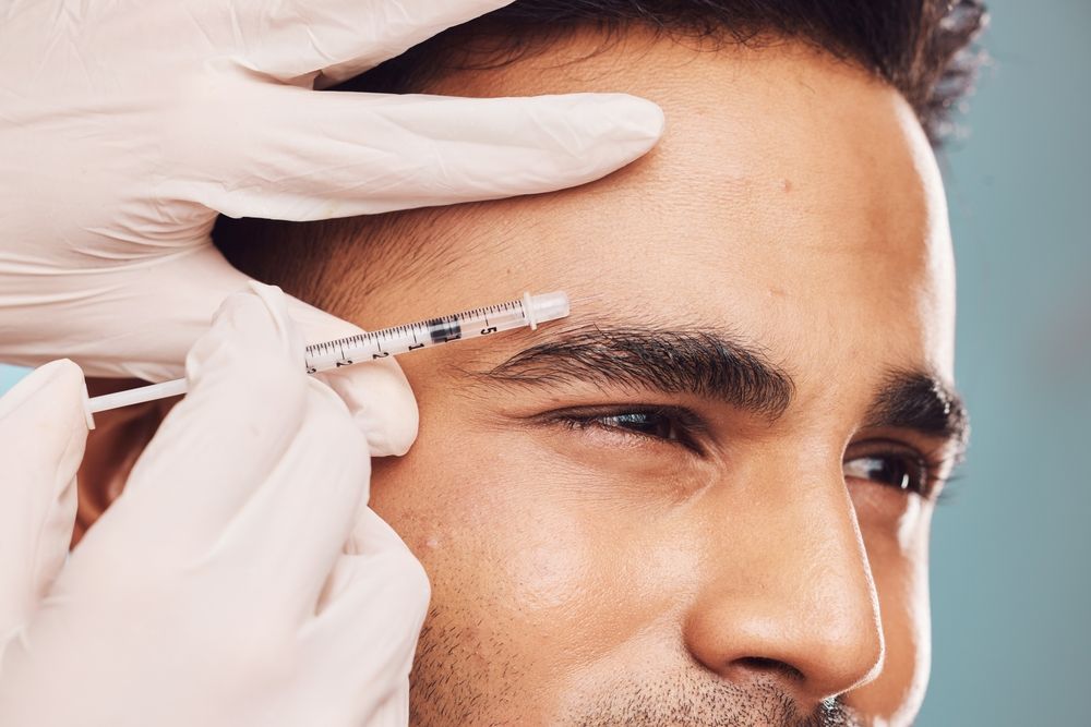 A woman is giving a man a botox injection in his forehead.