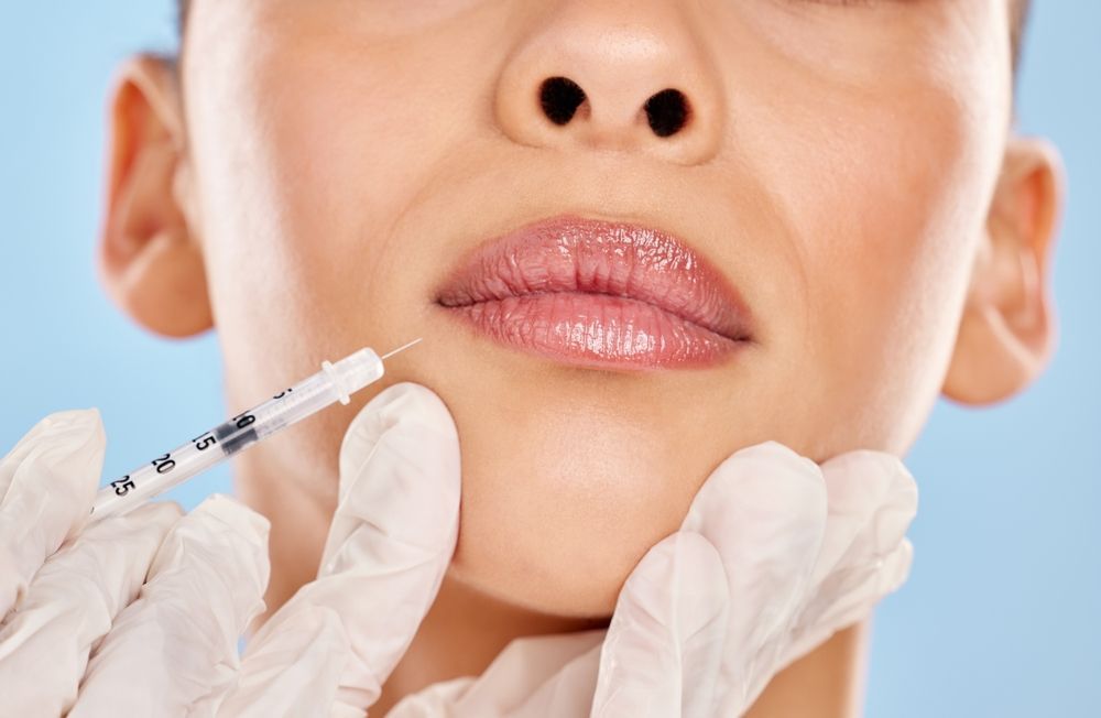 A woman is getting a botox injection in her lips.