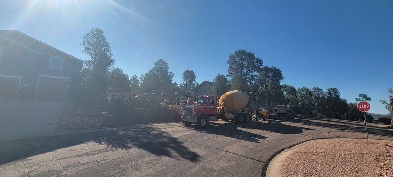 Construction truck with concrete mixer on a sunny suburban street near houses and trees