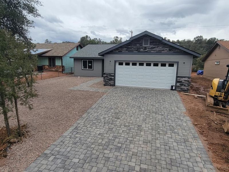 Gray house with a white garage and stone driveway in a residential area