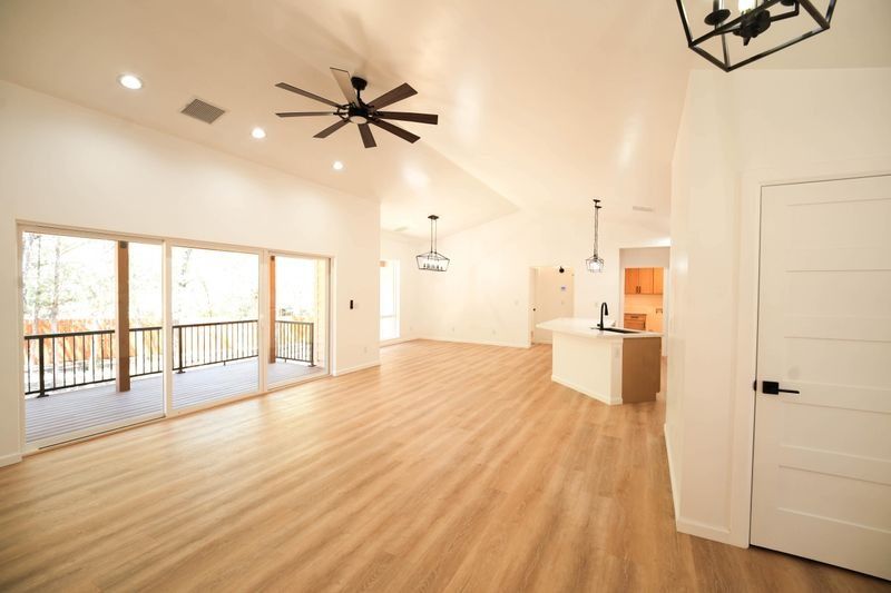 Bright open living room with wood floors, ceiling fans, large windows, and a white kitchen island