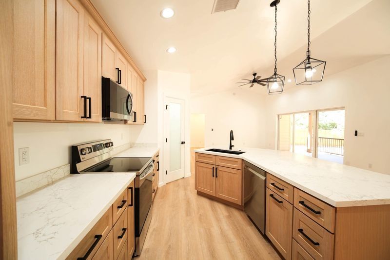 Bright modern kitchen with wood cabinets, white countertops, island, and hanging pendant lights