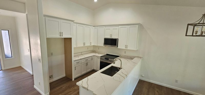 Bright white kitchen with island, white cabinets, stainless appliances, and gray walls