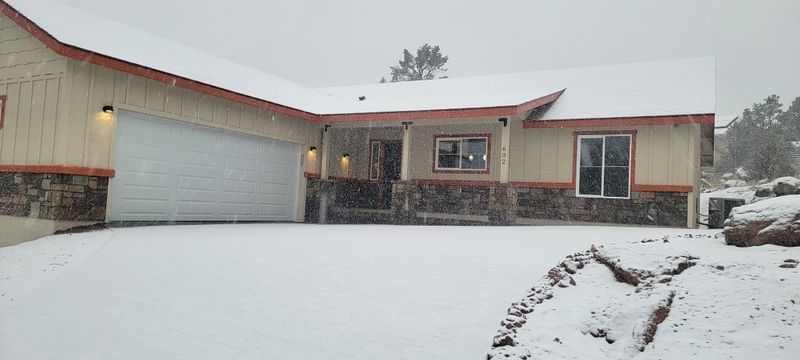 Snow-covered suburban house with a garage and front yard during a snowfall