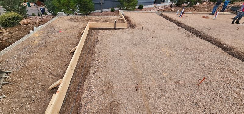 Construction site with wooden formwork laid out on a gravel foundation under preparation