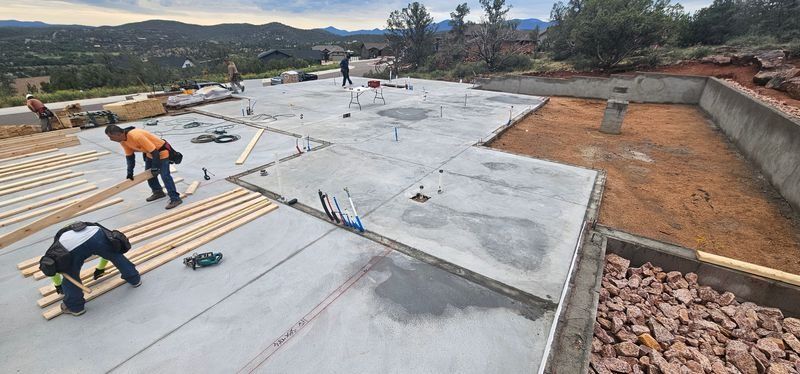 Workers installing a flat rooftop membrane on a construction site with tools and materials spread across the roof.