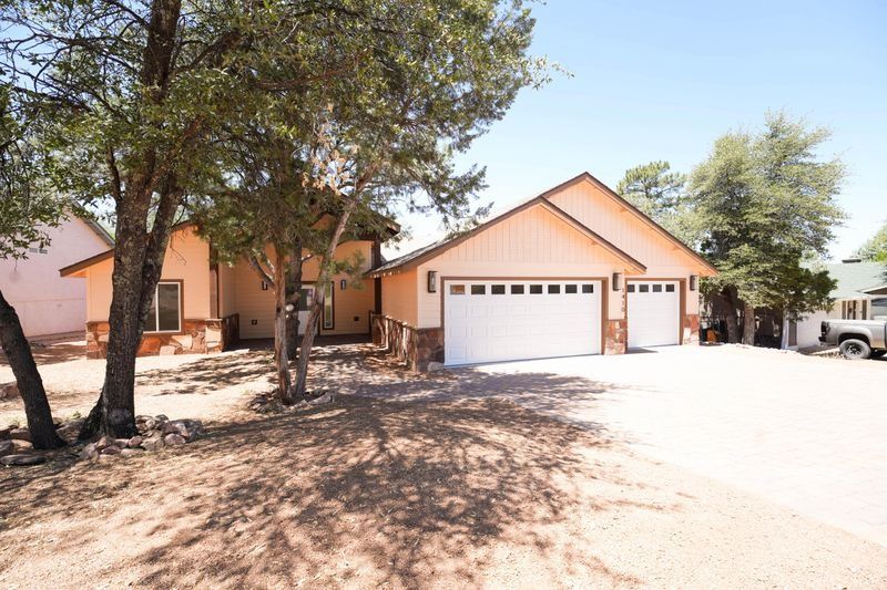 Suburban house with peach exterior, two-car garage, and trees in a sunny driveway