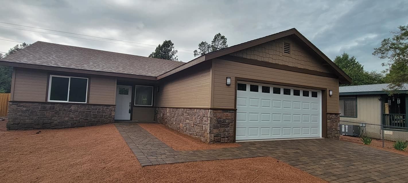 Single-story suburban house with brick and stone exterior, white garage door, and a gravel driveway