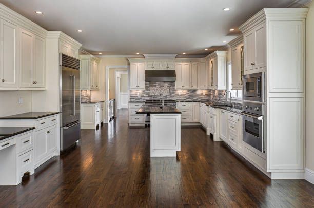 A large kitchen with white cabinets and hardwood floors.