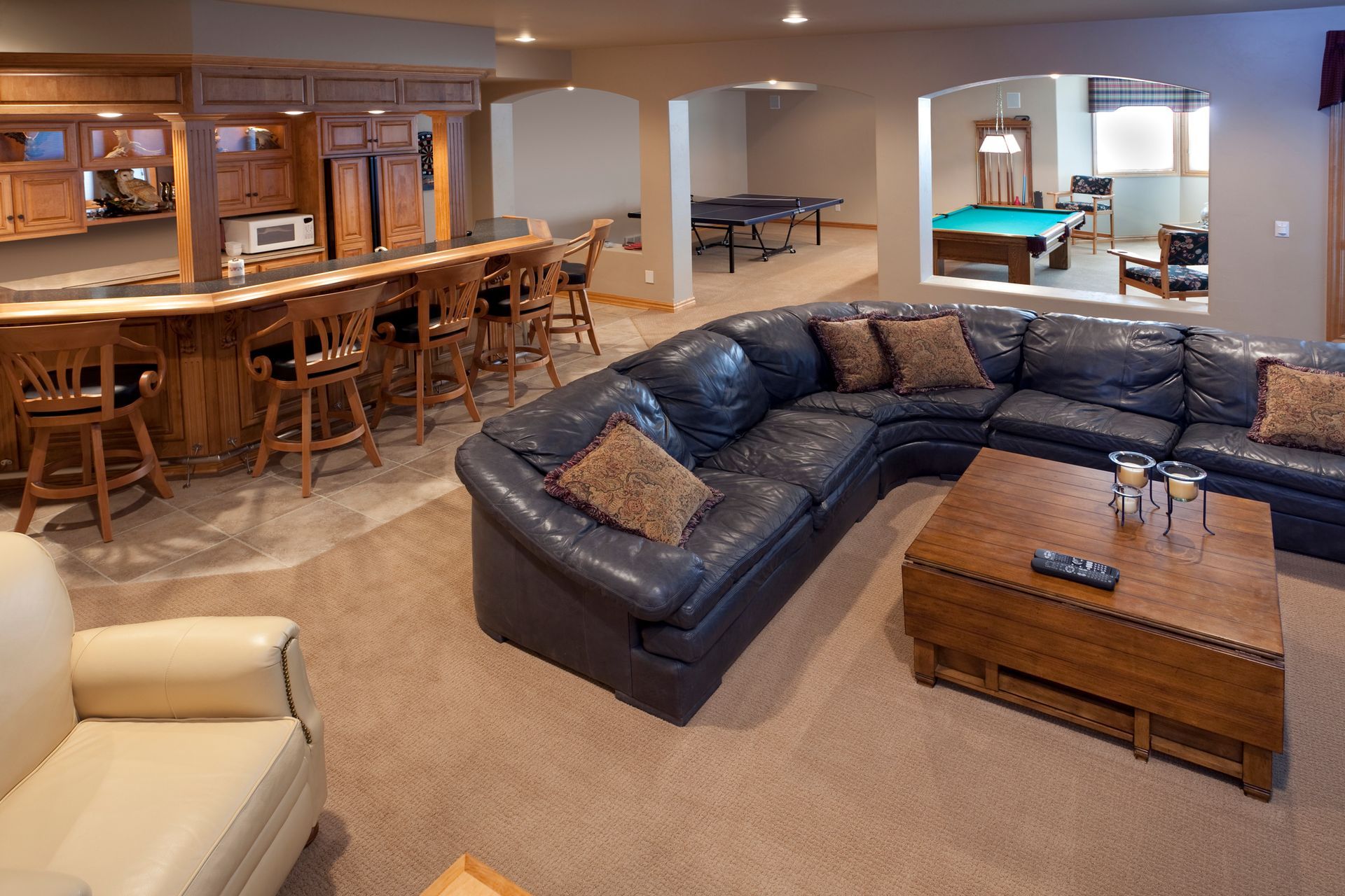 A living room with a large sectional couch and a pool table