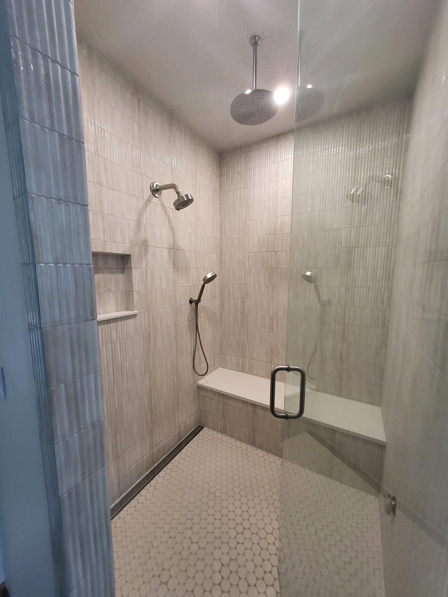 Bathroom renovation in progress: green tile installation on red wall, level in place. Buckets on floor.
