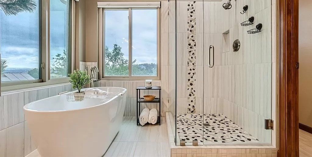 Luxurious bathroom with a soaking tub, shower, and a window overlooking trees.