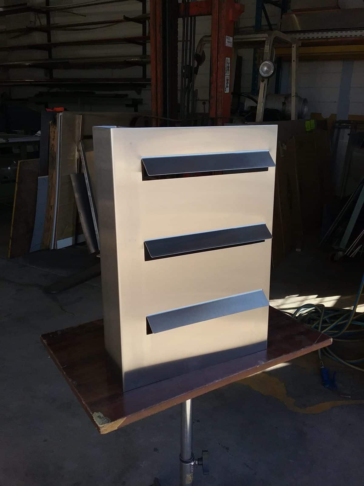 Stainless Steel Mailbox With Three Horizontal Slots, Sitting on a Table in a Workshop — Highlander Metals in Parramatta, NSW