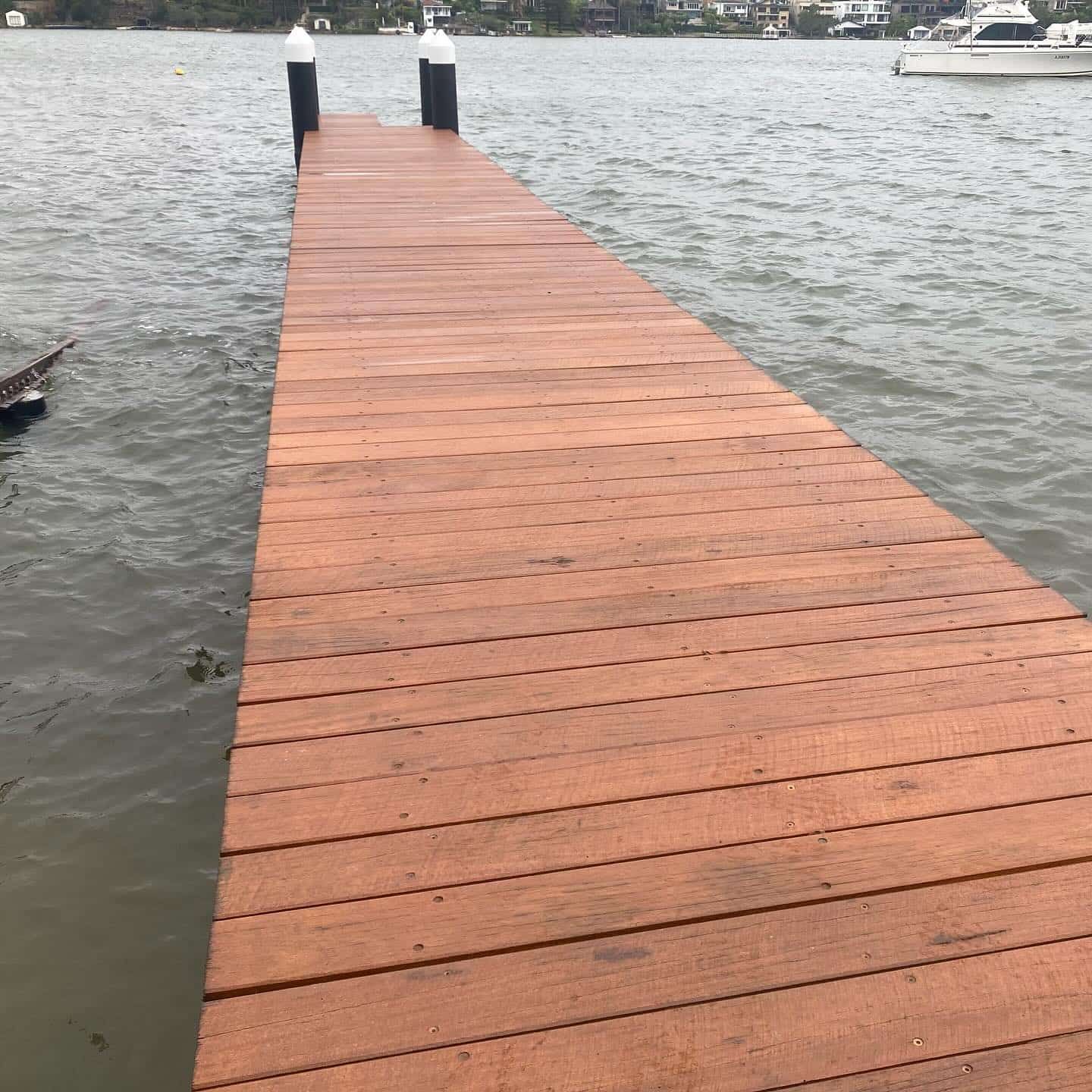 Wooden Dock Extending Into Water, Black Posts, Brown Wood, Overcast Day — Highlander Metals in Parramatta, NSW