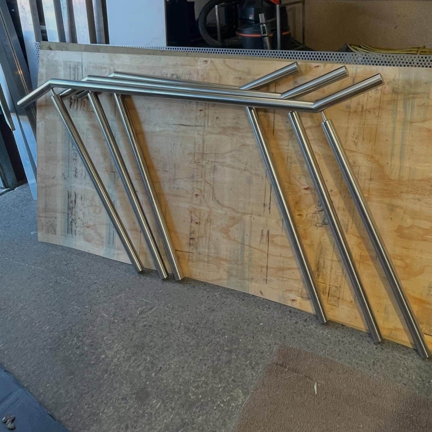 Silver Metal Handrails Stacked on a Wooden Surface — Highlander Metals in Kirrawee, NSW