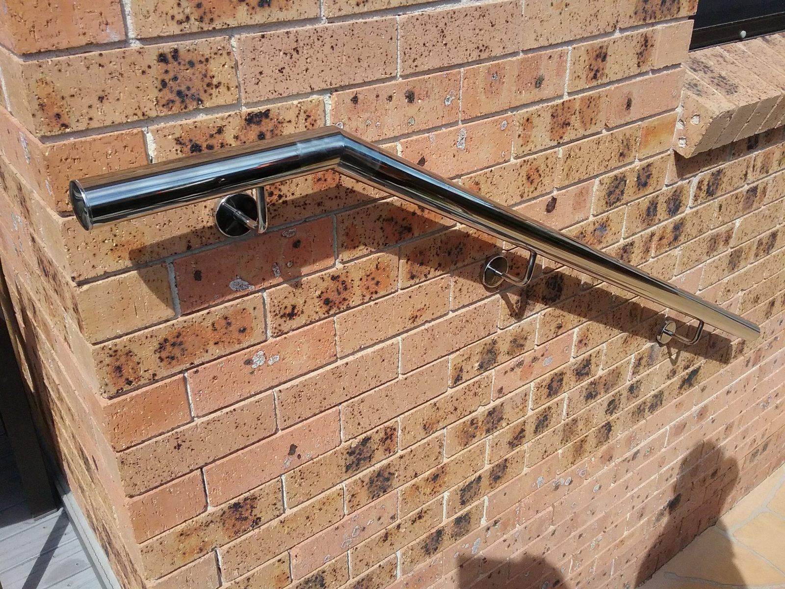 A metal handrail mounted on a brown brick wall above steps — Highlander Metals in Kirrawee, NSW