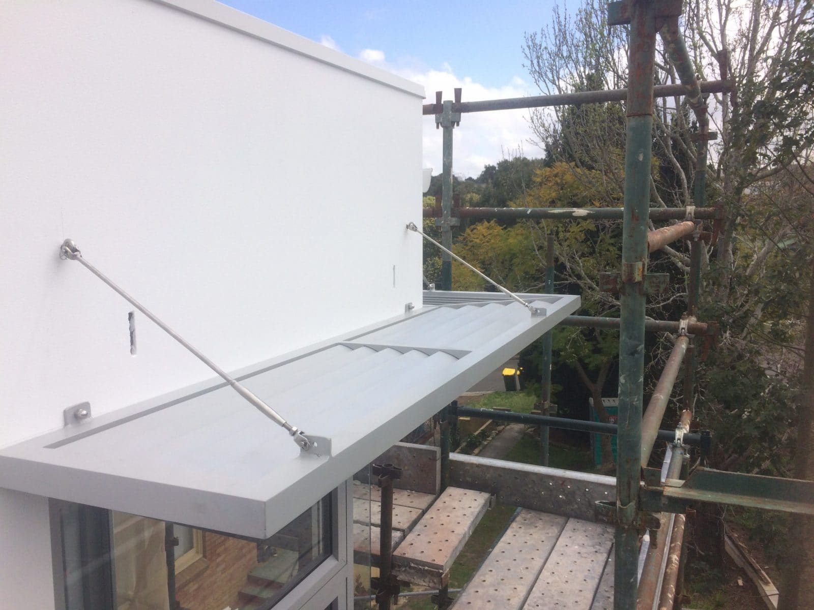 A Silver Awning on a White Building, Supported by Cables and Scaffolding — Highlander Metals in Kirrawee, NSW
