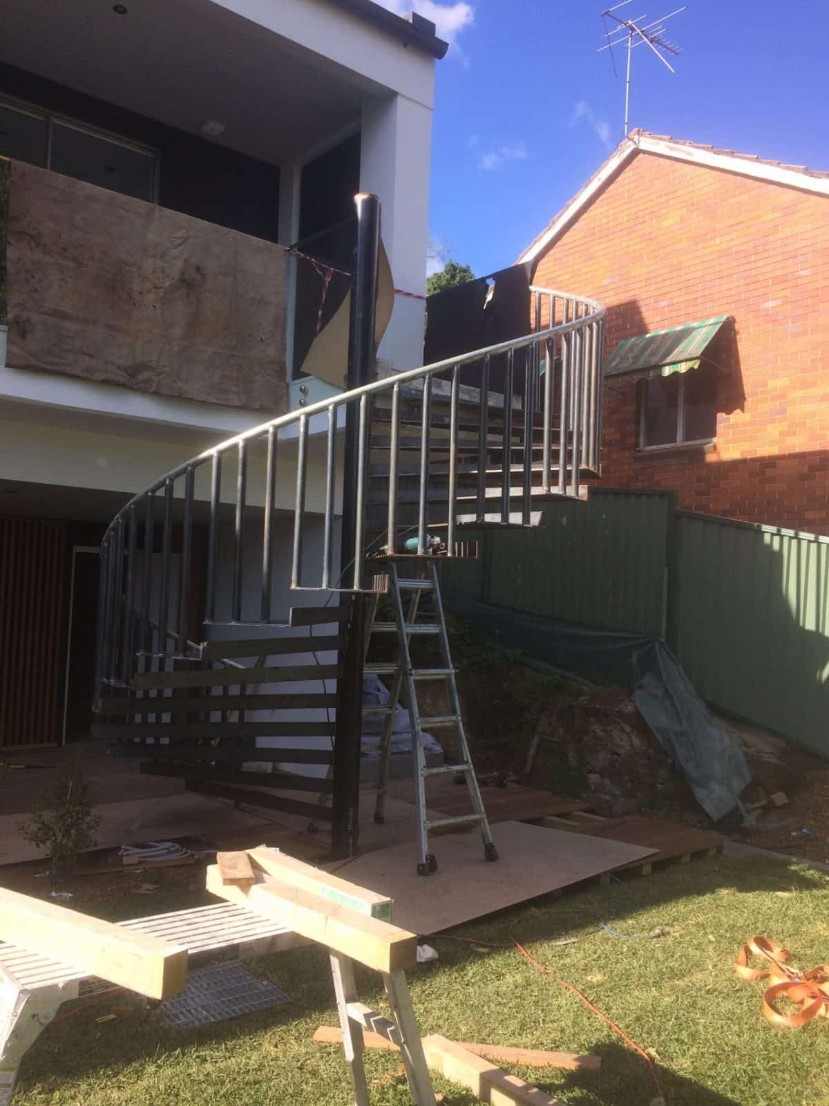 A spiral staircase under construction stands outside a two-story residential building near a grassy yard — Highlander Metals in Kirrawee, NSW