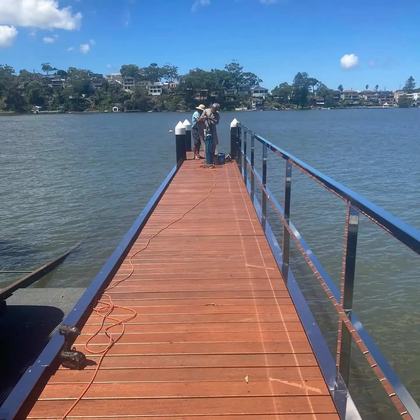 Wooden Pier With Metal Railing Extending Into Water; People Working on Pier — Highlander Metals in Parramatta, NSW