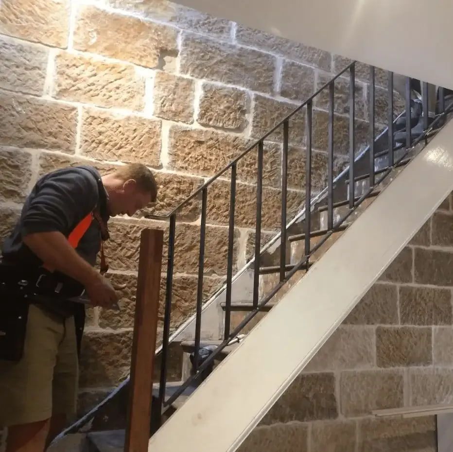 Man Installing a Stair Railing Next to a Brick Wall — Highlander Metals in Kirrawee, NSW
