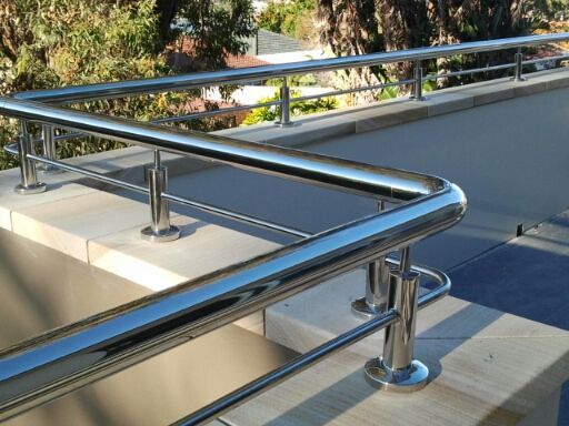 Stainless steel railings mounted on a light-coloured stone ledge overlooking an outdoor area with trees in the background — Highlander Metals in Kirrawee, NSW
