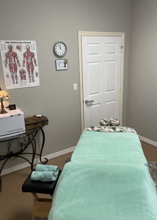A massage table in a room with a clock on the wall.