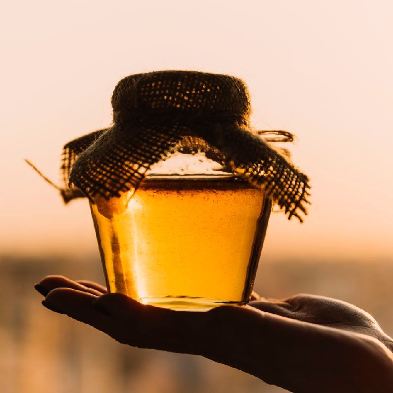 Una persona sostiene un tarro de miel en su mano.