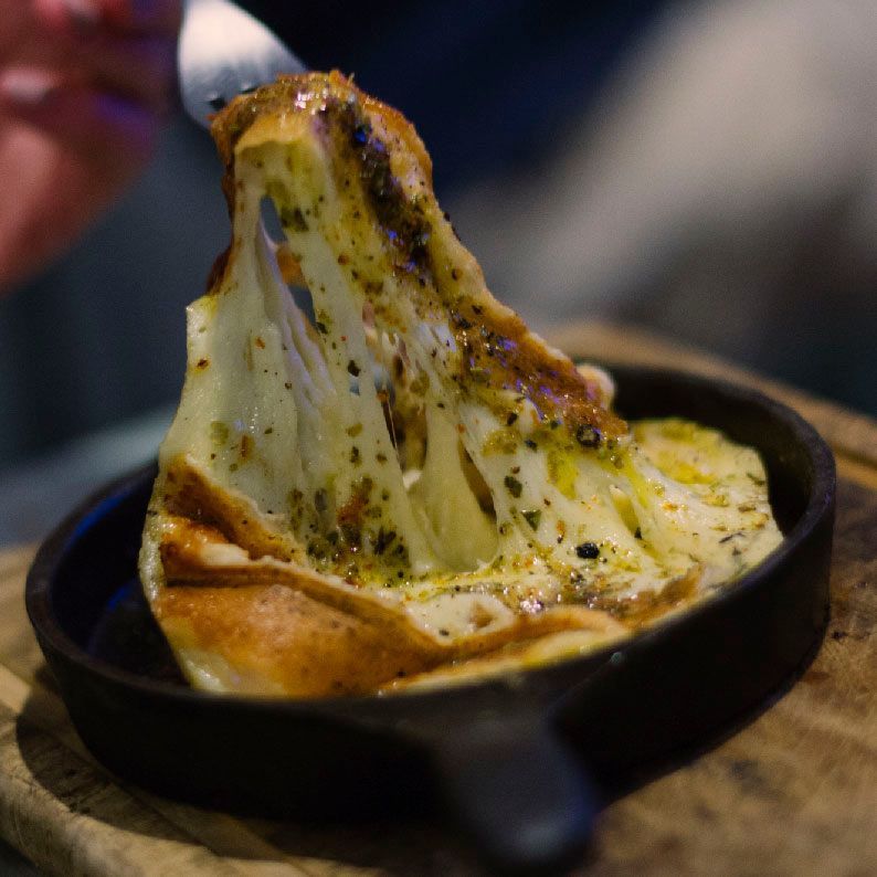 Una persona está sacando un trozo de queso de una sartén.