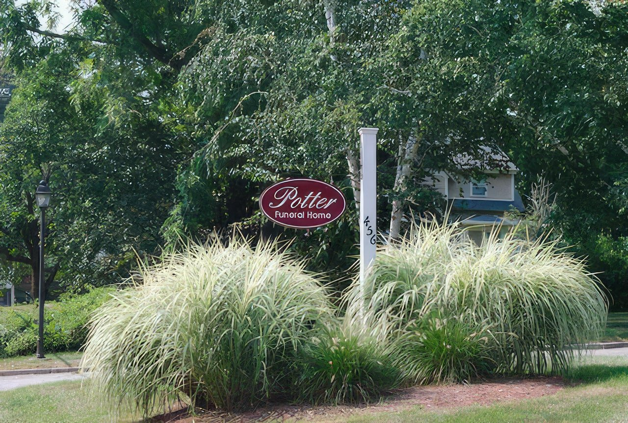 A sign that says potter is surrounded by tall grass and trees