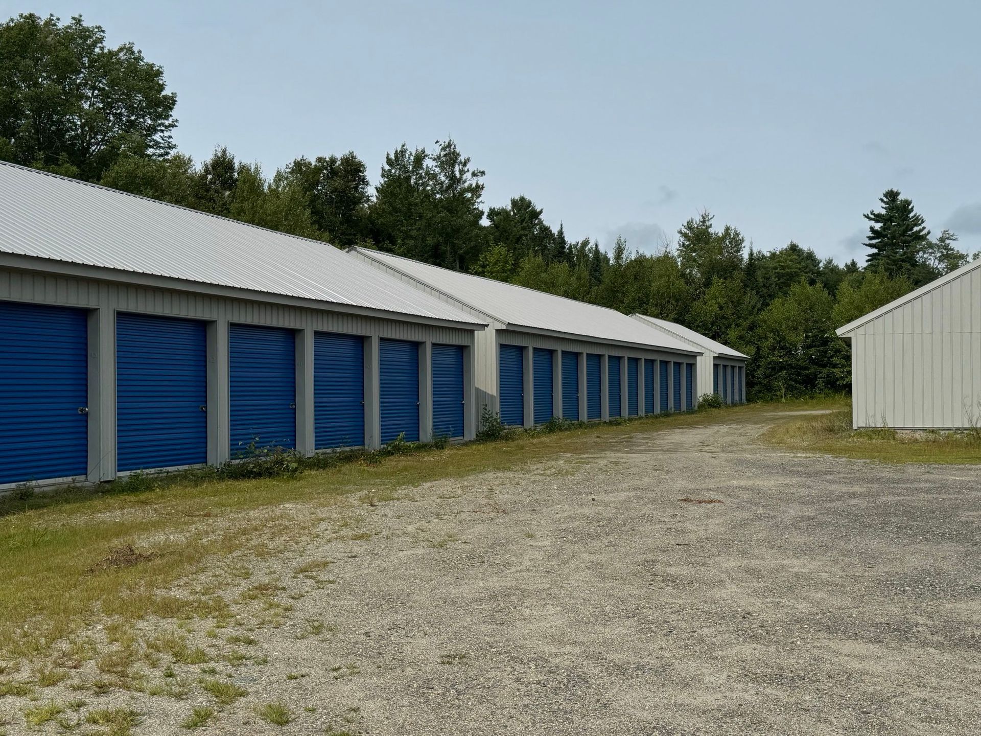 Four gray storage buildings with blue doors.