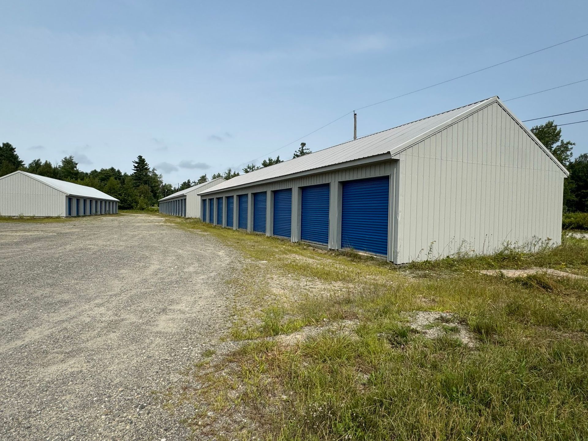 Three gray storage buildings with blue doors.