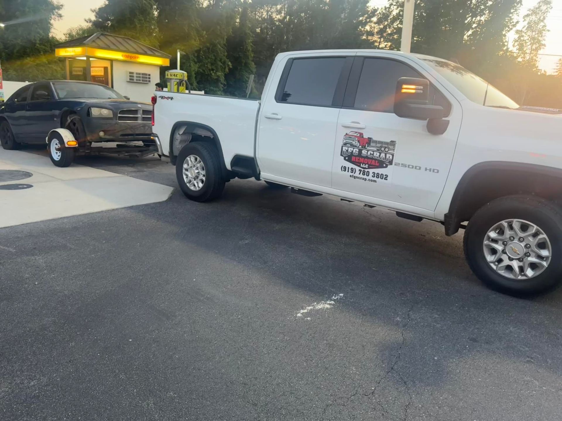 A white truck is towing a black car on a trailer