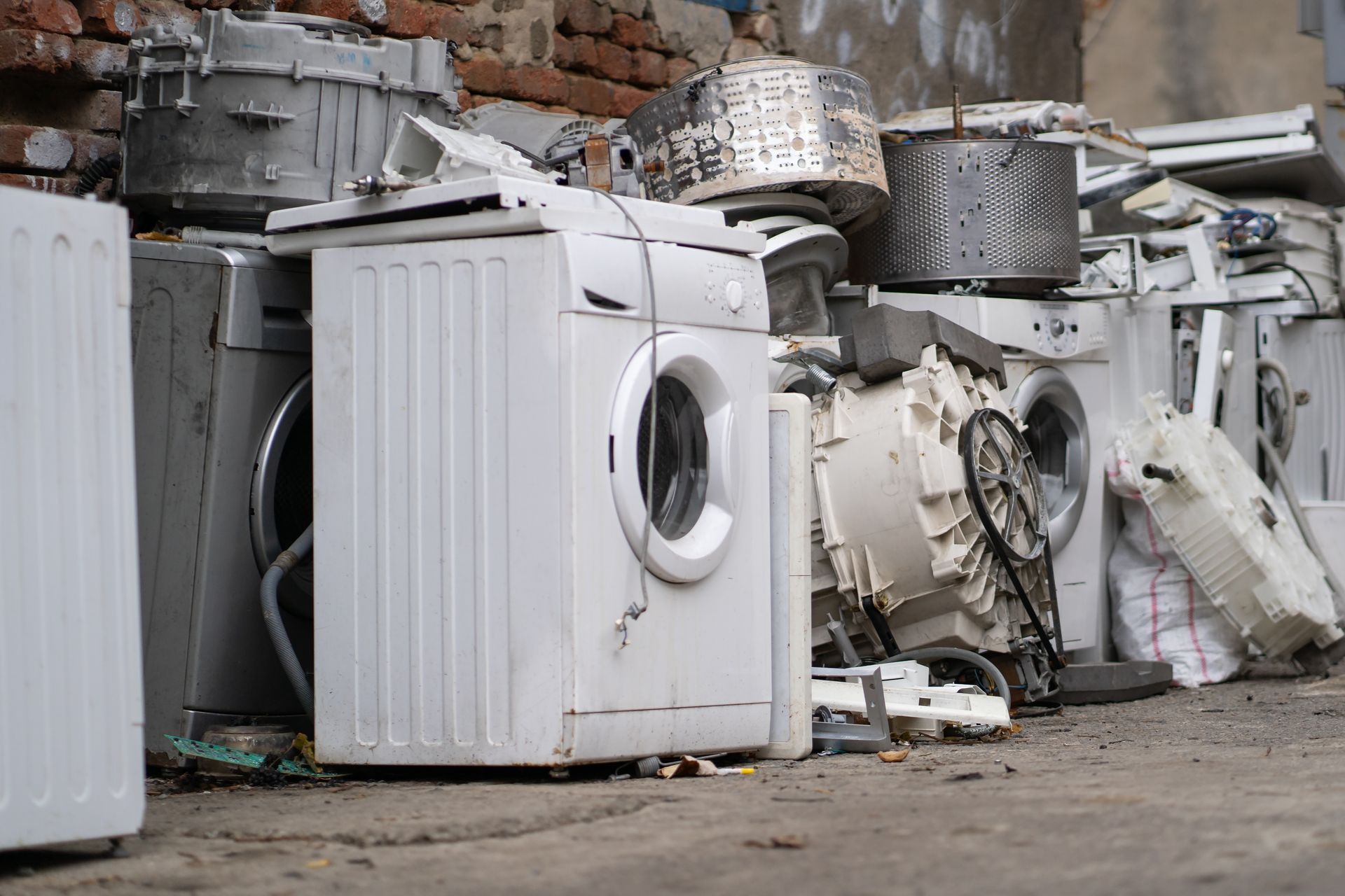 A bunch of old washing machines are sitting on top of each other on the ground.