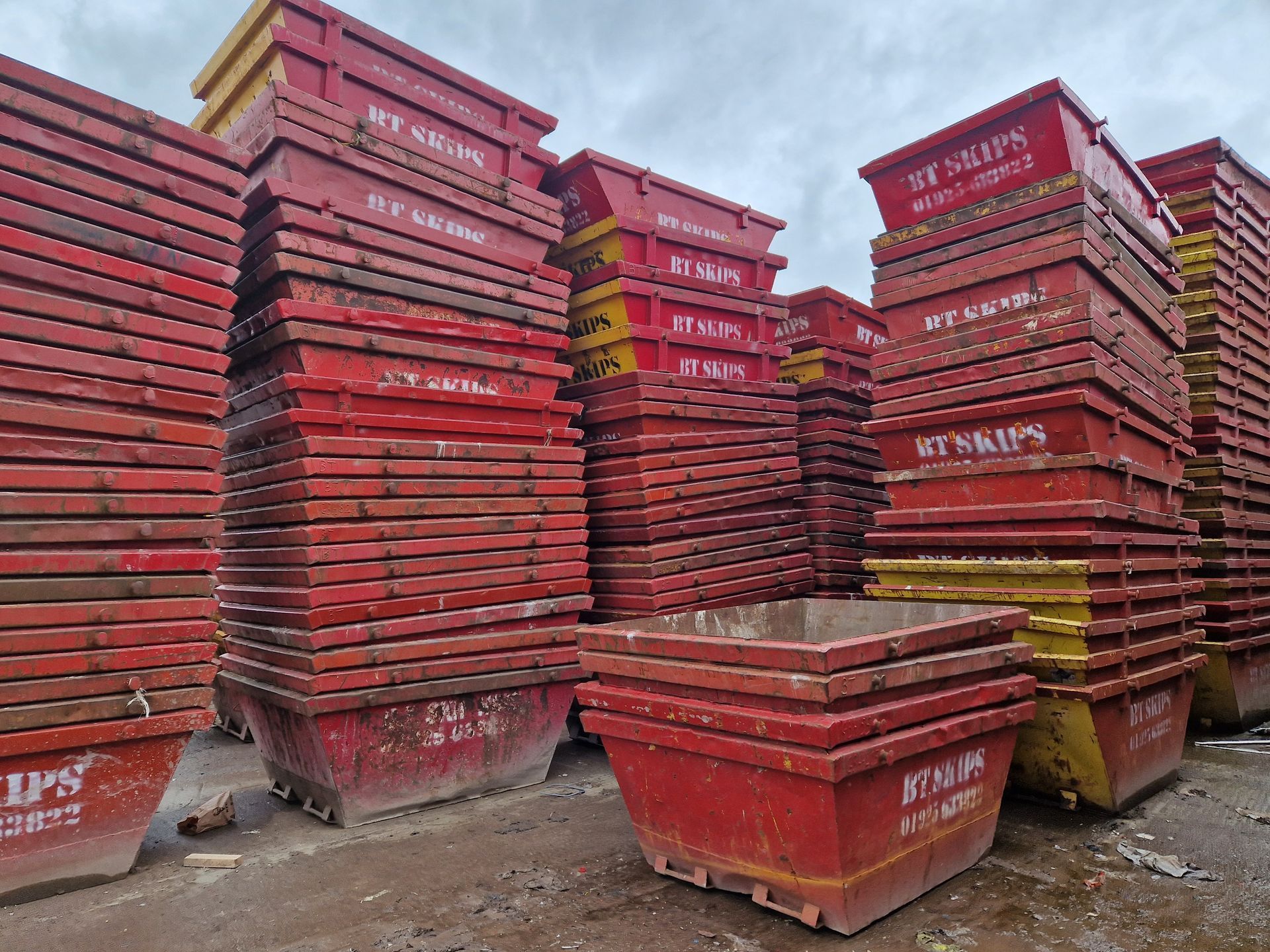 A pile of red and yellow dumpsters are stacked on top of each other.