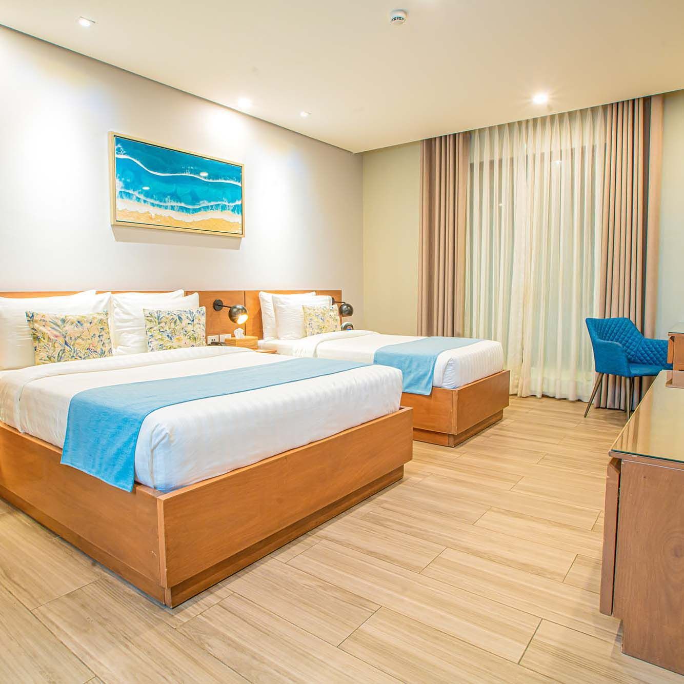 Elegant twin bedroom with coastal artwork, blue accents and wooden furnishings at a Palawan resort