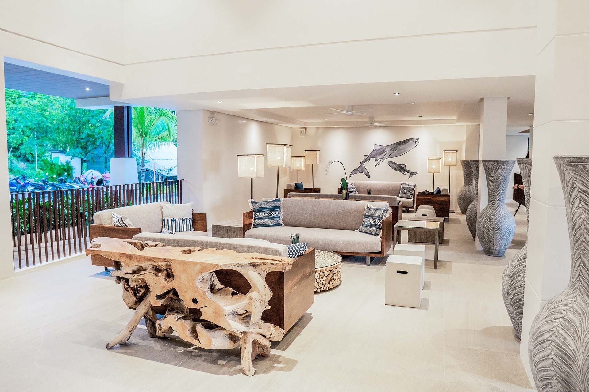 A hotel lobby with a couch , table , chairs and vases in an el nido hotel