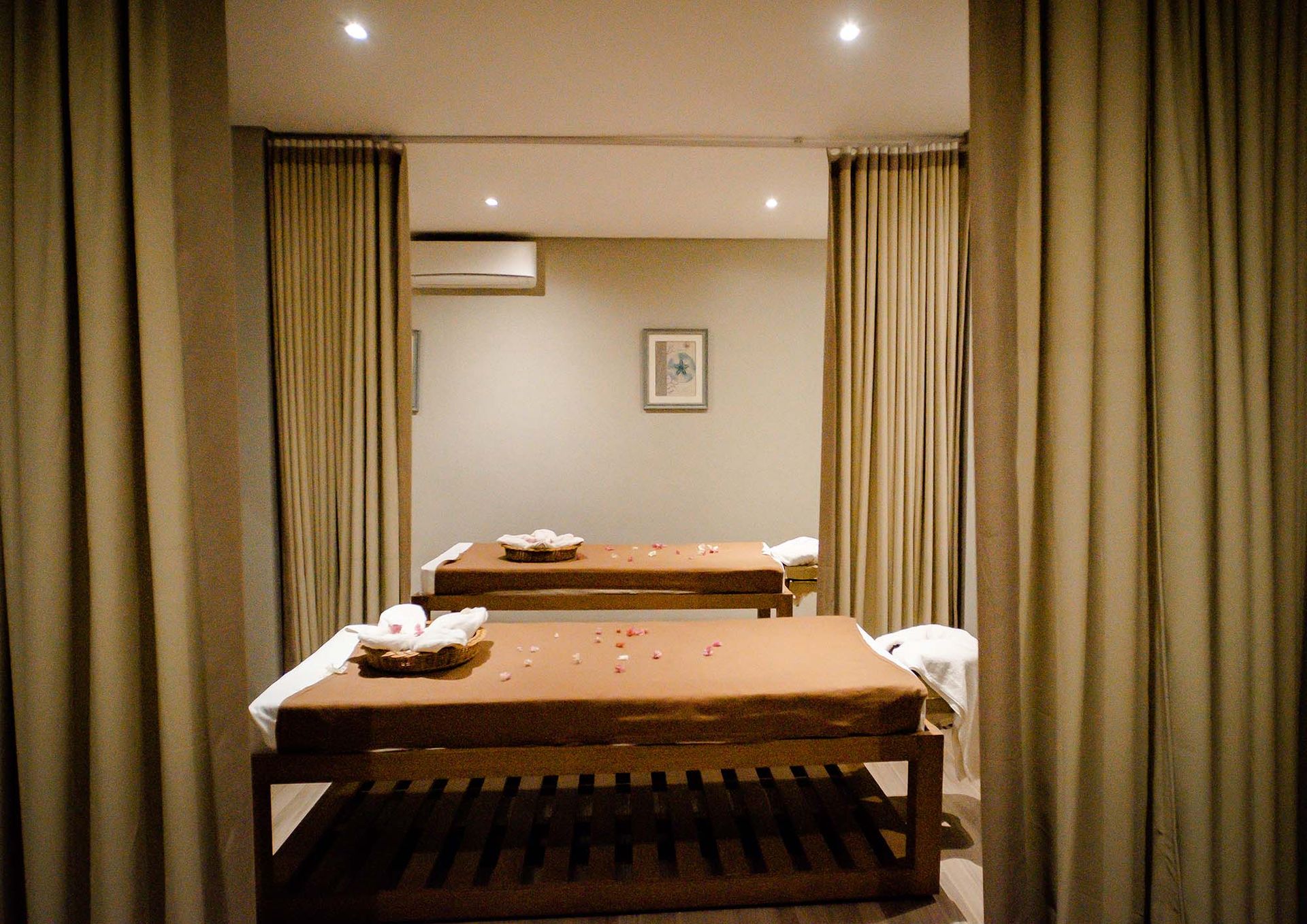 A couple of massage tables in a room with curtains.