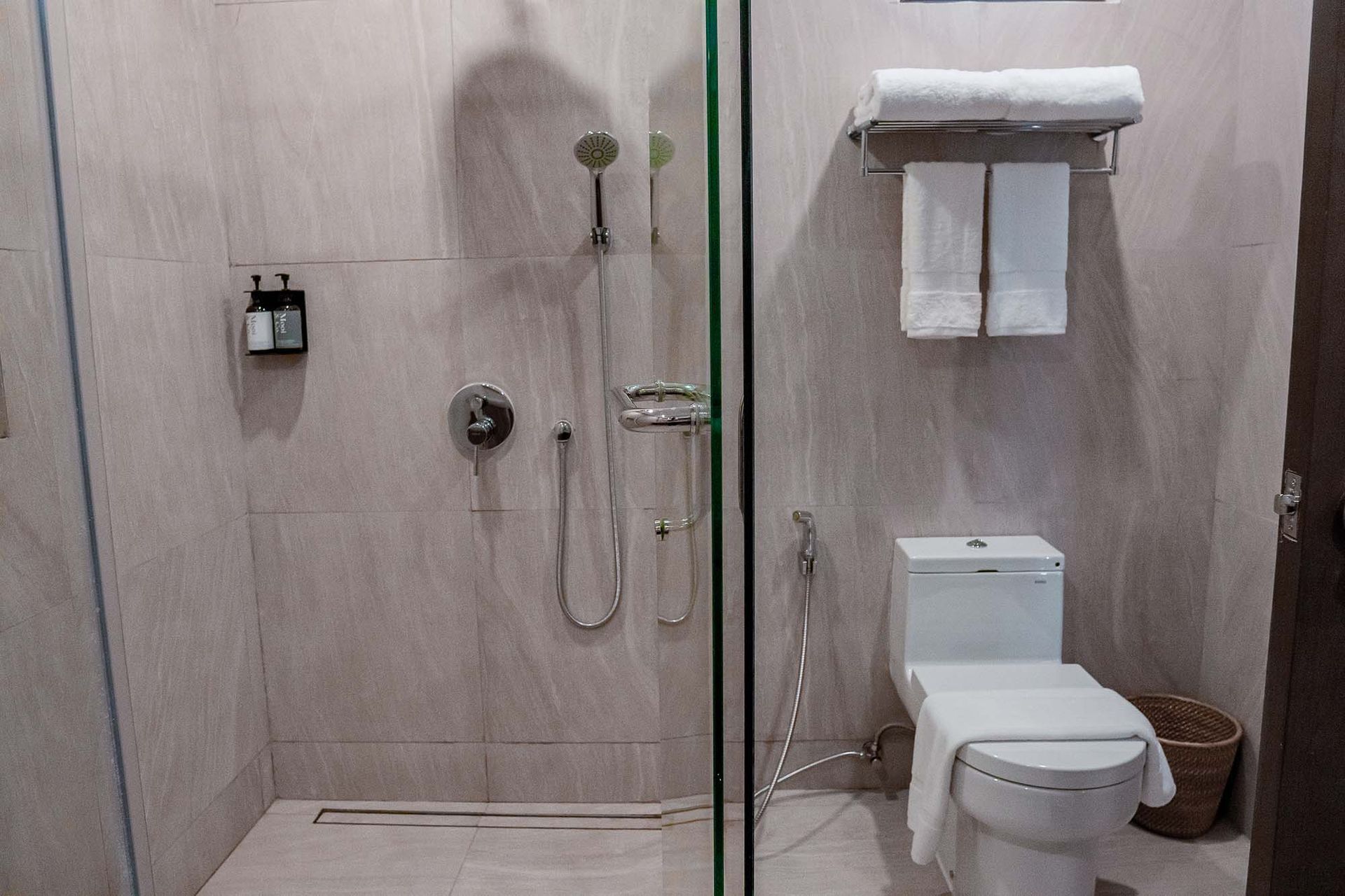 Modern bathroom with glass shower enclosure, rainfall showerhead, white toilet and neatly folded towels