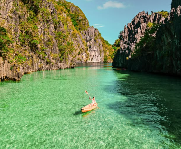 Kayaking through El Nido's turquoise lagoon surrounded by limestone cliffs, a popular activity in Palawan
