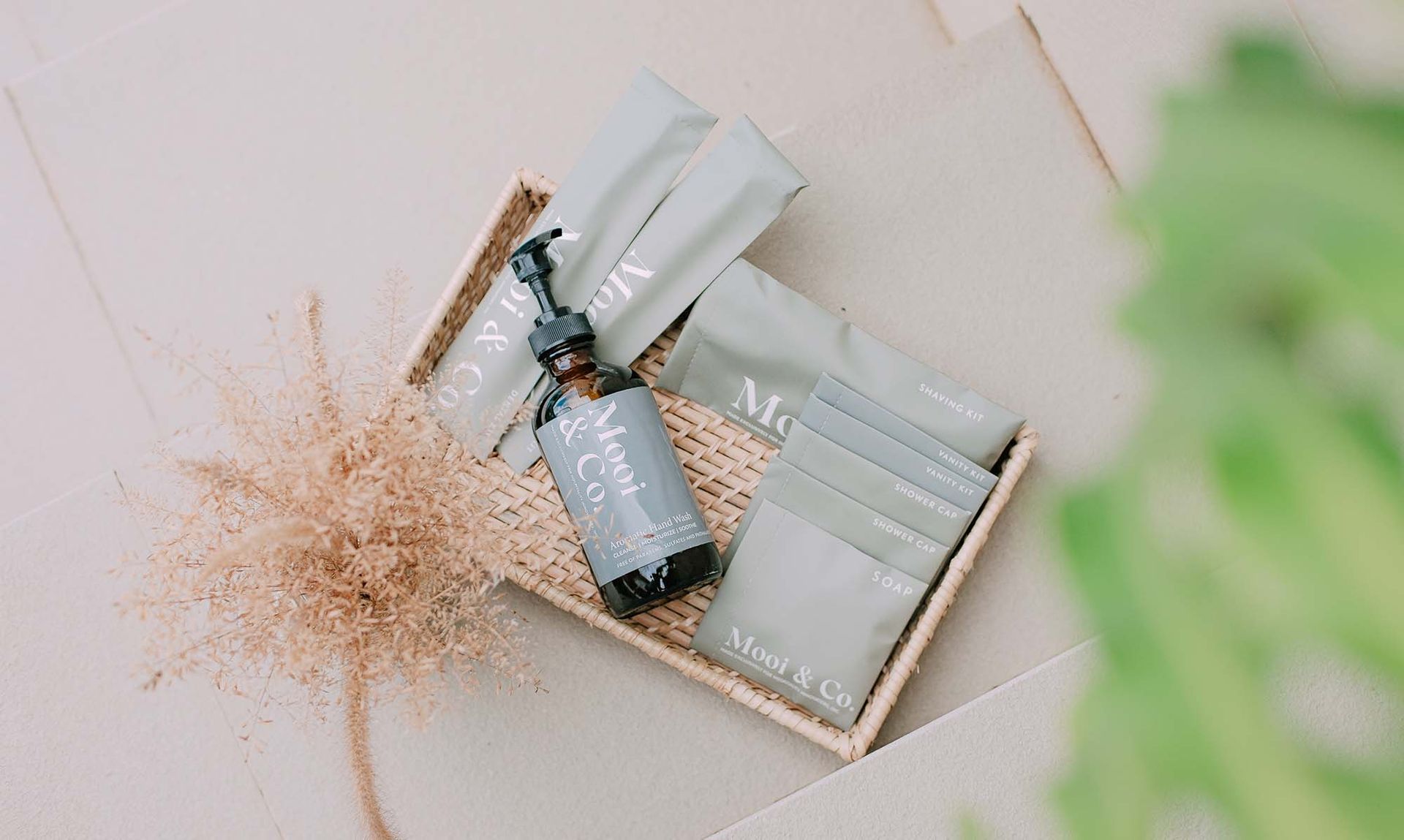 Luxury toiletry set featuring Moods & Co branded products arranged in a woven basket with dried flowers
