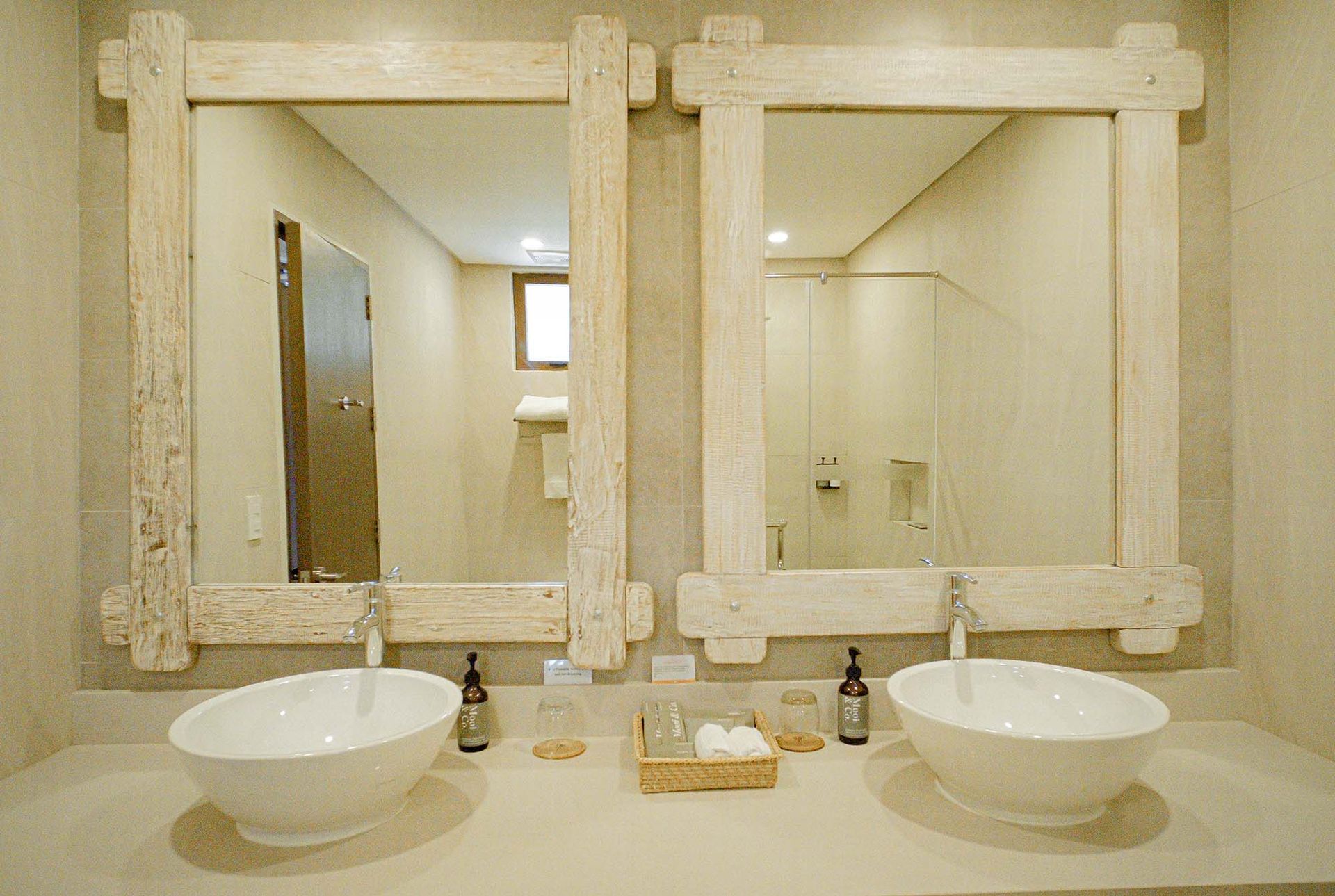 Elegant bathroom with double vessel sinks, framed mirrors, and neatly arranged toiletries on a marble countertop